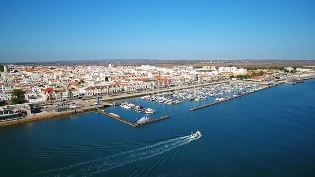 Aerial view of a fishing boat leaving the harbor of vila real de santo antonio, a beautiful coastal town in the algarve region of southern portugal with its characteristic white buildings