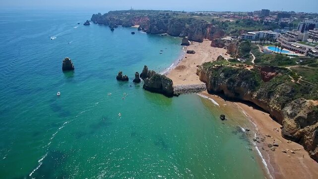 Breathtaking aerial footage showcasing the stunning golden cliffs, rock formations, and turquoise waters of camilo beach and ponta da piedade in the algarve region of southern portugal