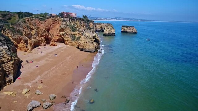 Stunning aerial perspective showing the picturesque camilo beach and the impressive ponta da piedade rock formations in lagos, algarve, with tourists enjoying the sunny summer day