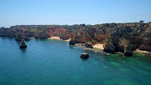 Dramatic drone perspective revealing the stunning ponta da piedade coastline. Featuring the famous camilo beach with its golden sand. Turquoise ocean water. And spectacular rock formations in algarve