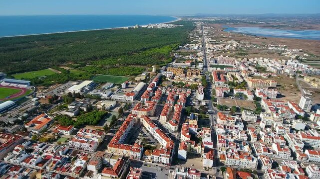 Spectacular aerial perspective flying over the coastal town of vila real de santo antonio, showcasing the urban landscape meeting the vast green forest and the beautiful atlantic ocean coastline