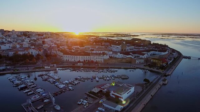 Picturesque aerial view capturing the historic old town of faro and its charming marina, with yachts moored in calm waters as the golden sun rises over the beautiful algarve coastline in portugal