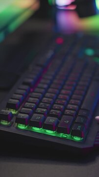 Close up view of mechanical keyboard with RGB backlighting focusing on keys and hands typing. scene features vibrant green lighting under keycaps while fingers press various buttons