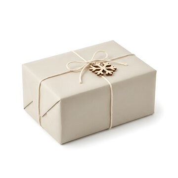 Christmas gift box wrapped in beige paper with twine bow and wooden snowflake ornament isolated