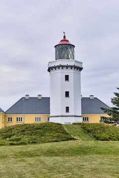 Hanstholm, Thisted, Denmark - 09 August 2026: View of Hanstholm Fyr, a historic white lighthouse with a red lantern room, standing on a grassy hill against a cloudy sky.