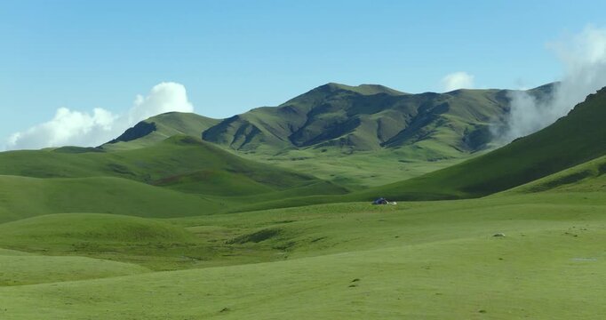 Badimalika region, Bajura, Nepal, Aerial shot over the vast green alpine meadows and rolling hills in Triveni Patan grassland, surrounded by pristine nature and clouds.