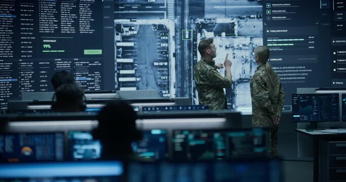 Army Military Surveillance Monitoring Control Room: Commander and Officer in Camouflage Uniform Hold a Meeting and Talk Near Screen Showing Satellite Map While Ai Analysts Plan a Tactical Defence.