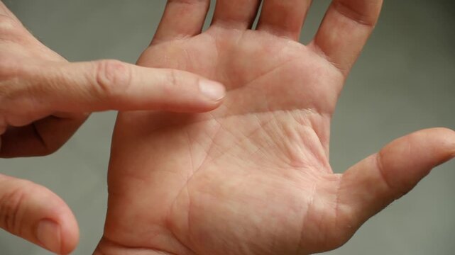 Close up of a palm reader finger tracing the lines on a person's hand during a chiromancy session to predict the future, a spiritual and esoteric practice for divination and fortune telling