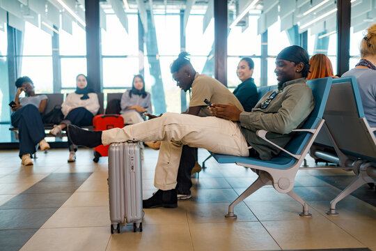 People waiting in a terminal while sitting on chairs with luggage