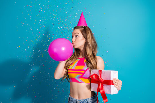 Girl celebrating with a pink balloon, wearing a colorful top, with confetti and a gift box on a vibrant blue backdrop.