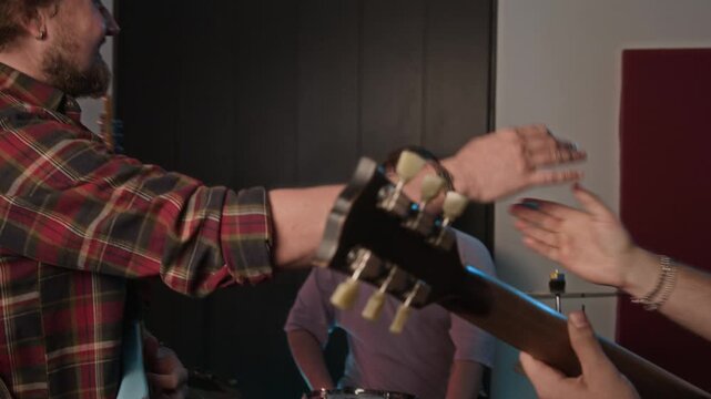 Caucasian musicians finishing band rehearsal, playing electric bass and drums before doing high fives. Footage suitable for music production, creative collaboration, and lifestyle marketing