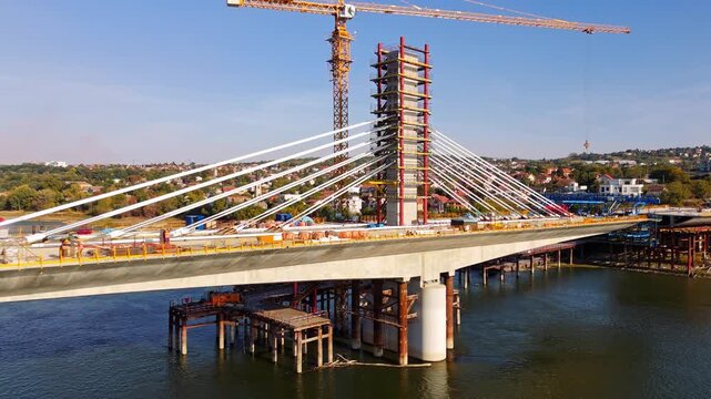 Aerial view of a cable-stayed bridge under construction with a large crane over the Danube river in Novi Sad, Vojvodina, Serbia.