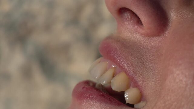 Teeth mouth closeup woman talking in profile outdoors under bright natural sunlight showing skin and dental details