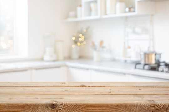 Blurred bright festive kitchen interior background with empty wooden tabletop mockup in front