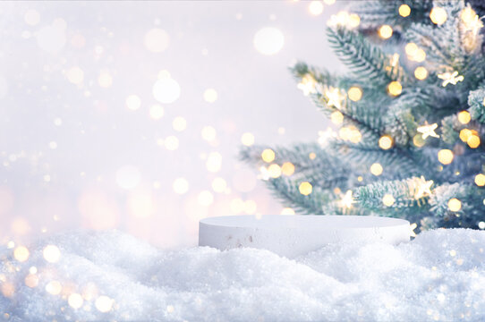 White empty stone podium and magical Christmas background with blurred tree, snow and golden bokeh lights