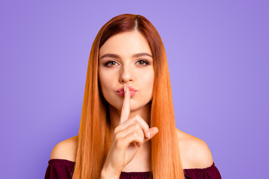 Portrait of red straight-haired attractive cute nice funny young girl, showing shh silence with finger touching lips. Isolated over bright vivid yellow background