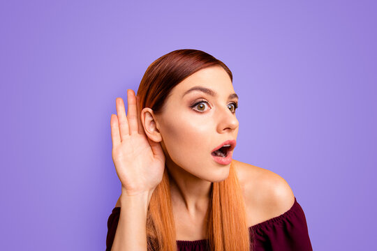 Portrait of red straight-haired attractive cute nice curious cunning young girl, overhearing with one ear, shocked, opened mouth. Isolated over bright vivid yellow background