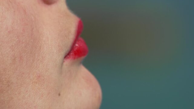 Vibrant strawberry flavor enjoyed by a woman biting into fresh produce outdoors under natural sunlight. Extreme macro static side profile shot.