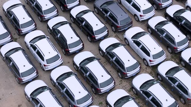 Aerial view of rows of new white and dark grey cars parked in an orderly lot in Gdansk, Poland.