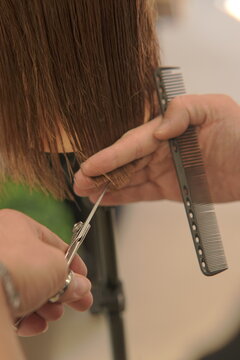Close-up shot of a professional hairstylist's hands precisely cutting and styling hair in a modern beauty salon