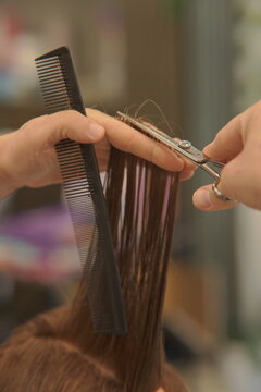 Close-up shot of a professional hairstylist's hands precisely cutting and styling hair in a modern beauty salon