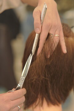 Close-up shot of a professional hairstylist's hands precisely cutting and styling hair in a modern beauty salon