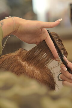 Close-up shot of a professional hairstylist's hands precisely cutting and styling hair in a modern beauty salon