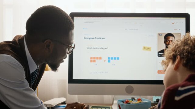 African American male tutor teaching Caucasian teenage boy math fractions on computer and guiding handwriting. Ideal for online education promos and tutoring service advertising