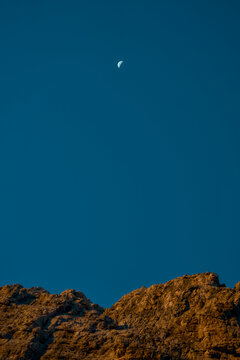 Luna calante nel cielo blu sopra le rocce illuminate dall'alba, Dolomiti di Brenta