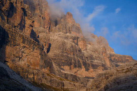 Tramonto sulle pareti rocciose delle Dolomiti di Brenta con nuvole sulla cima