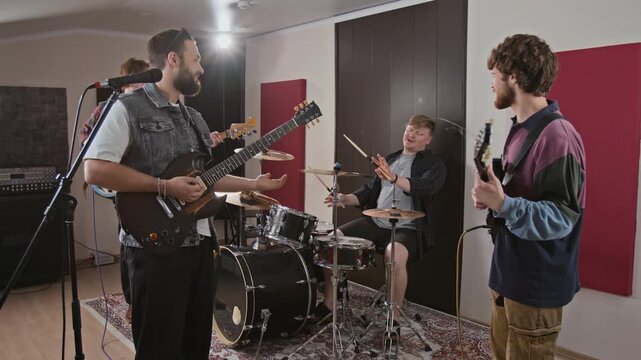 Young adult Caucasian rock band rehearsing with electric guitars and drums in studio. Footage fits music industry advertising and creative band promotion campaigns
