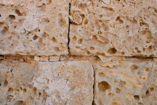 Eroded porous limestone block wall texture background from historic Maltese architecture