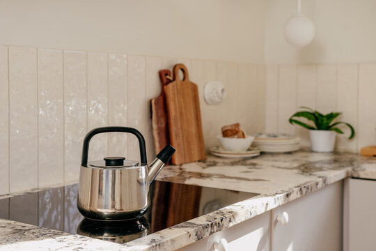 Induction hob with kettle on countertop in a modern kitchen setting