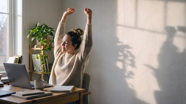 Female professional stretching beside her desk during a work break, showing relief, relaxation, self-care and healthy work-life balance