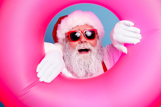 Santa Claus in sunglasses holding a pink inflatable pool float for summer holiday and Christmas vacation fun and festive beach party