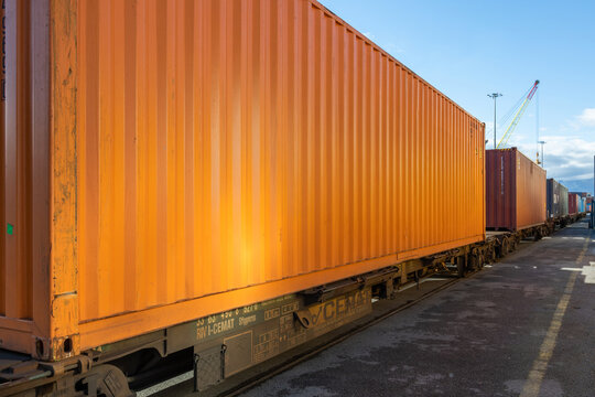 Orange shipping container on a freight train wagon at the port rail terminal
