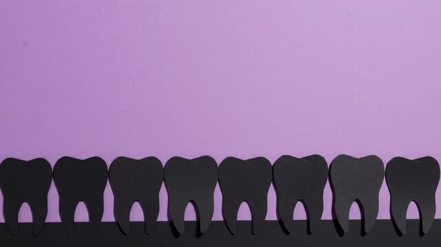 Black Paper Teeth Silhouettes Pivoting In A Row On A Purple Background
