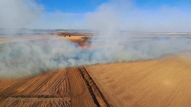 Aerial view of a large field fire with thick smoke rising over dry agricultural land in Serbia.