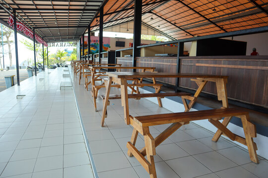 A row of empty wooden picnic tables and benches