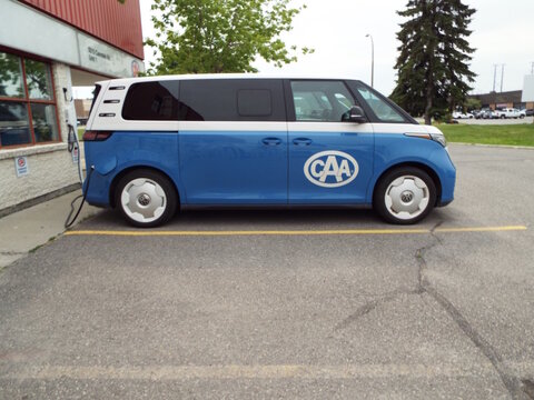 Orleans, Ontario, Canada &ndash; July 31, 2026: A blue and white electric van branded with the "CAA logo" is plugged in and parked outside a commercial building on Hoylake Crescent.