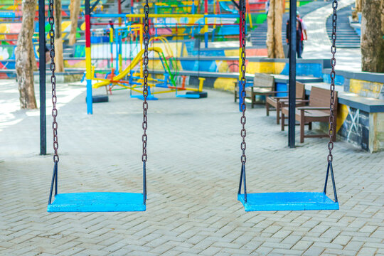 Close-up of two empty light blue wooden swings