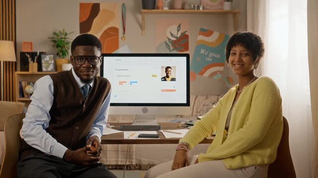 Portrait of smiling African American teenagers giving high five while studying at desk with computer. Footage suitable for online education, e-learning platforms, tutoring advertisements