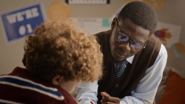 African American male tutor helping Caucasian teenager write notes during lesson. Clip suits marketing for private tutoring services, academic mentoring, and educational platform campaigns