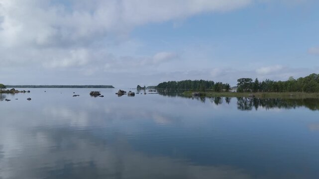 Aerial view of the calm waters of the Gulf of Finland with scattered rocks and forested coastline in Hamina, Kymenlaakso, Finland.