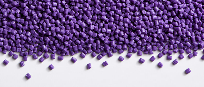 Close-up of a vibrant purple industrial plastic pellets background, forming a textured surface with a white copy space at the bottom, suitable for material science and recycling themes.