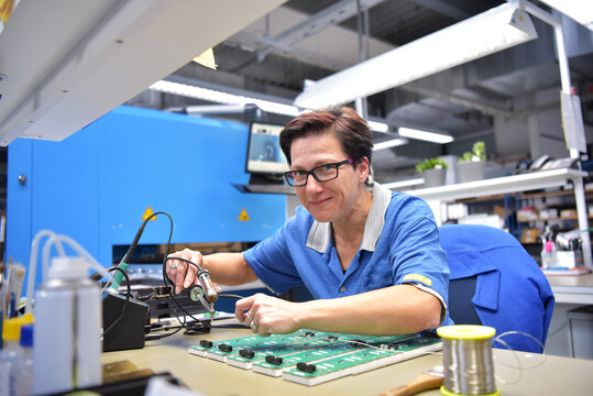 friendly woman working in a microelectronics manufacturing factory - component assembly and soldering