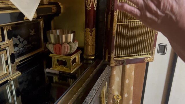 仏壇のおりんを鳴らして手を合わせる高齢者