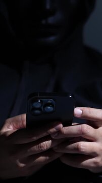 Phone scammers protection, mobile security, wearing black hood sitting in dark.