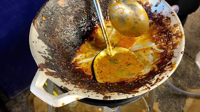 Close up shot of traditional sweet and spicy chili paste sauce with a metal spatula inside a hot wok pan at a street food market stall.