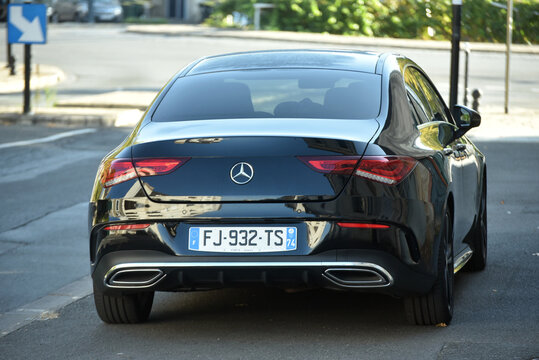 Bourges - France - 4 October 2026 - Rear three-quarter view of a black Mercedes-Benz CLA Coupe parked beside a curb on an urban street, with reflections of surrounding buildings on its glossy bodywork